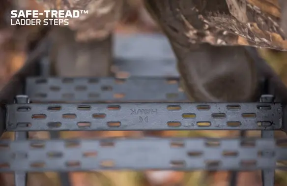 Boots on perforated metal ladder steps labeled "SAFE-TREAD™" from a high angle, suggest security and durability in an outdoor setting.