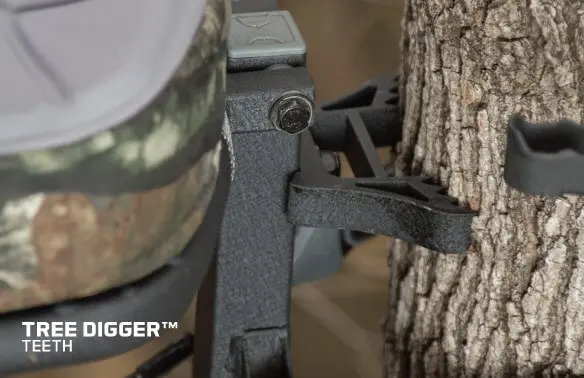 Close-up of a tree stand's tree digger teeth gripping a tree trunk. The metal teeth, designed for stability, are shown in rugged, outdoor conditions.