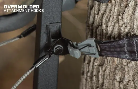 Close-up of an overmolded attachment hook securing a black strap to a tree trunk. The hook appears sturdy, conveying durability and reliability.