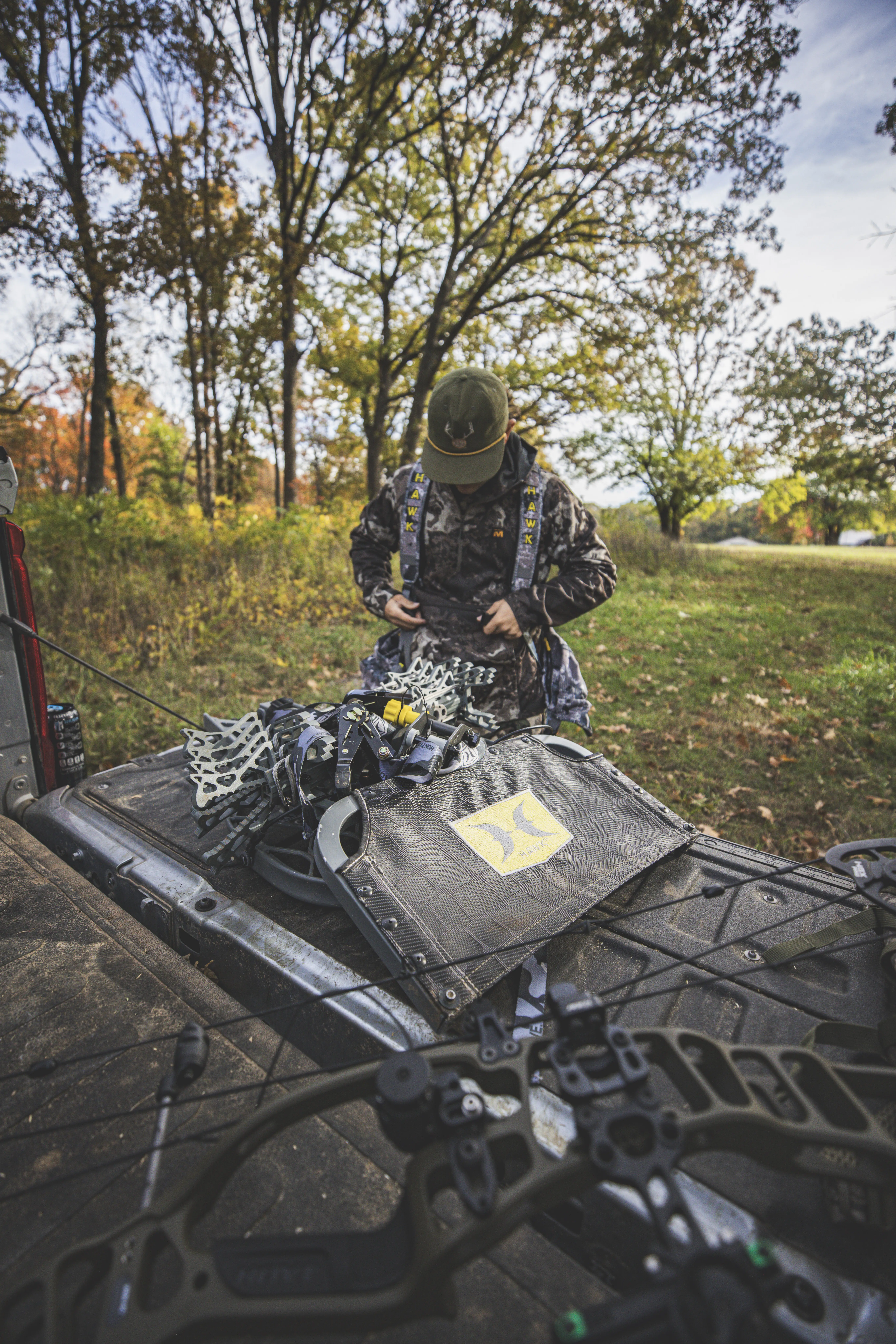 Hunter kneeling beside a whitetail buck with Hawk gear